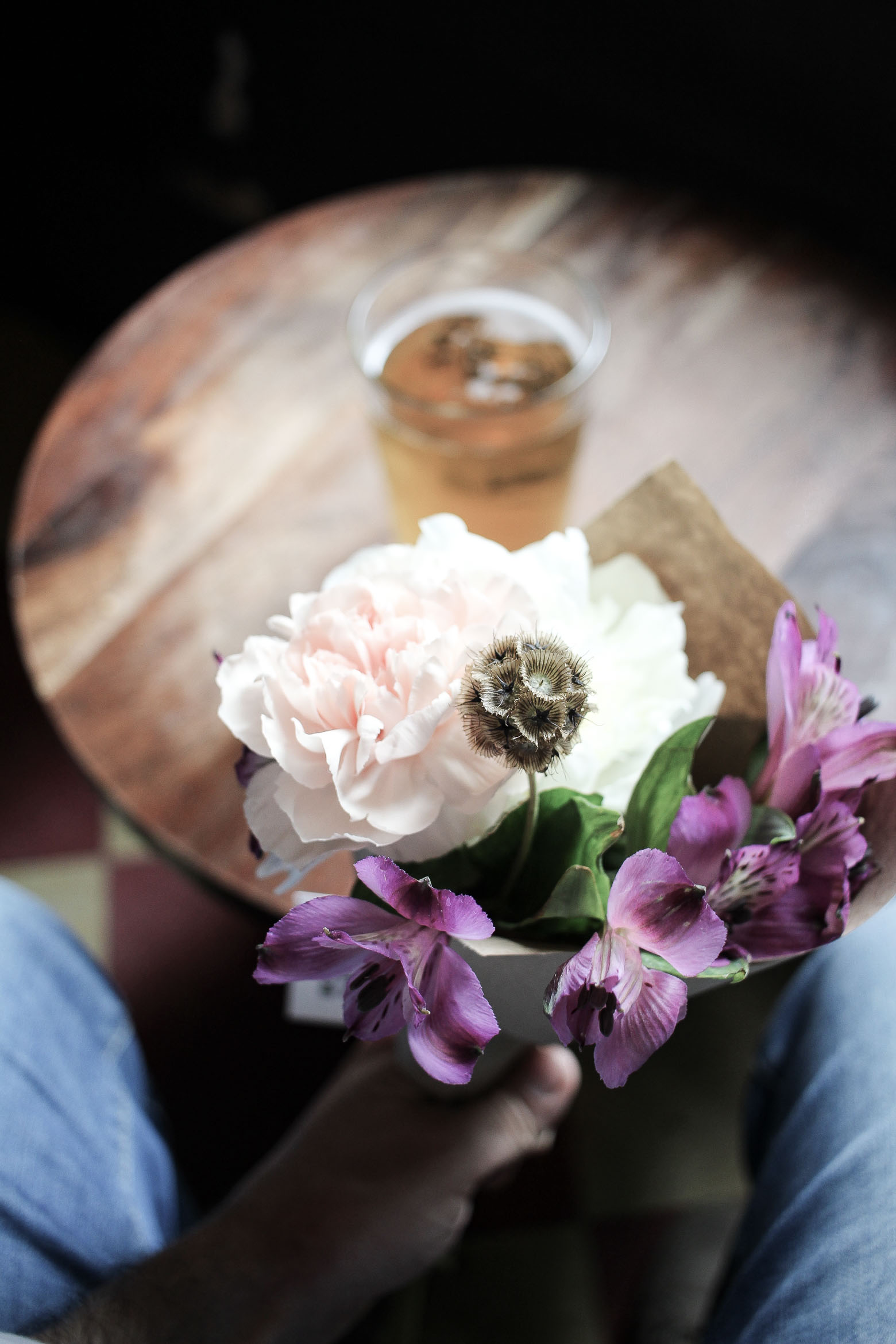 Man holding a flower bouquet and a beer in the background 