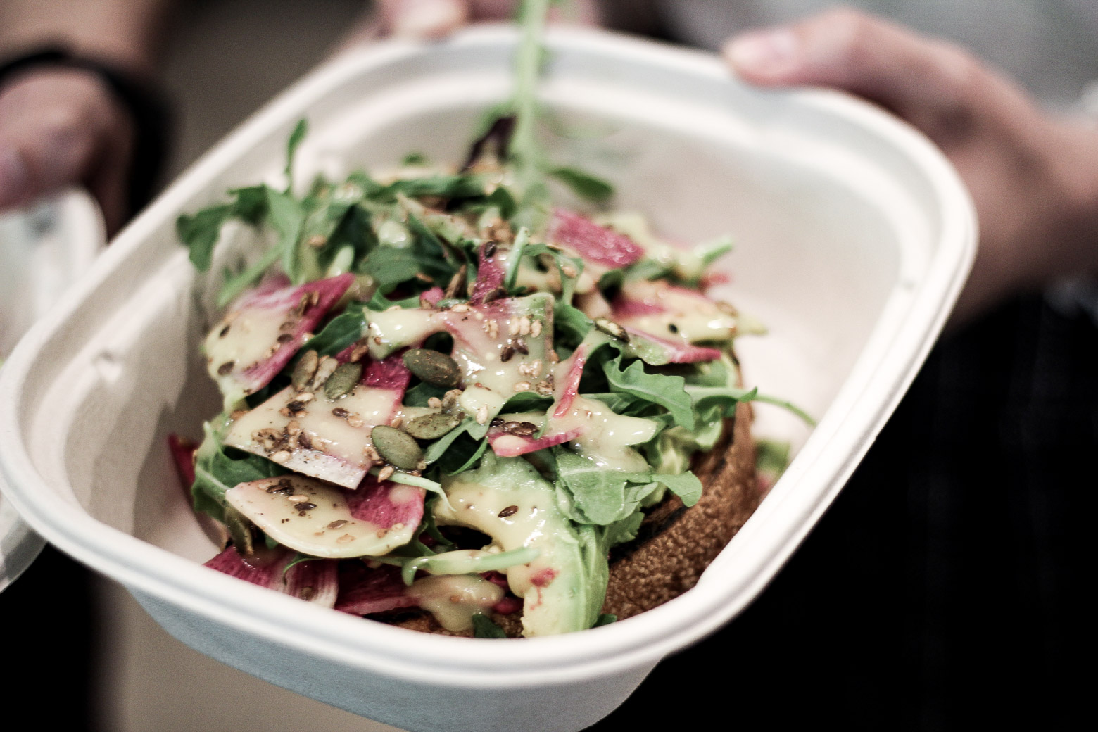 Avocado toast with arugula in to-go container 